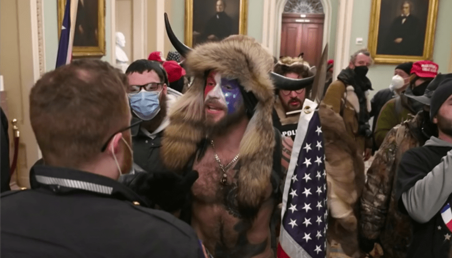 Capitol rioter and self-described "QAnon Shaman," Jake Angeli, costumed in symbolic paint and dress.